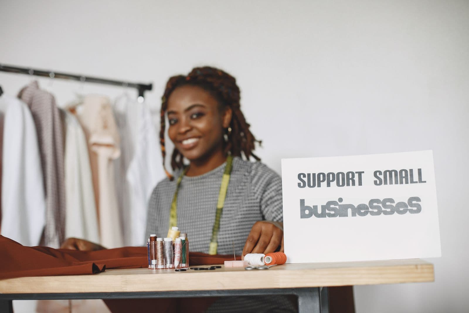 Small business owner at a desk with a sign supporting small businesses